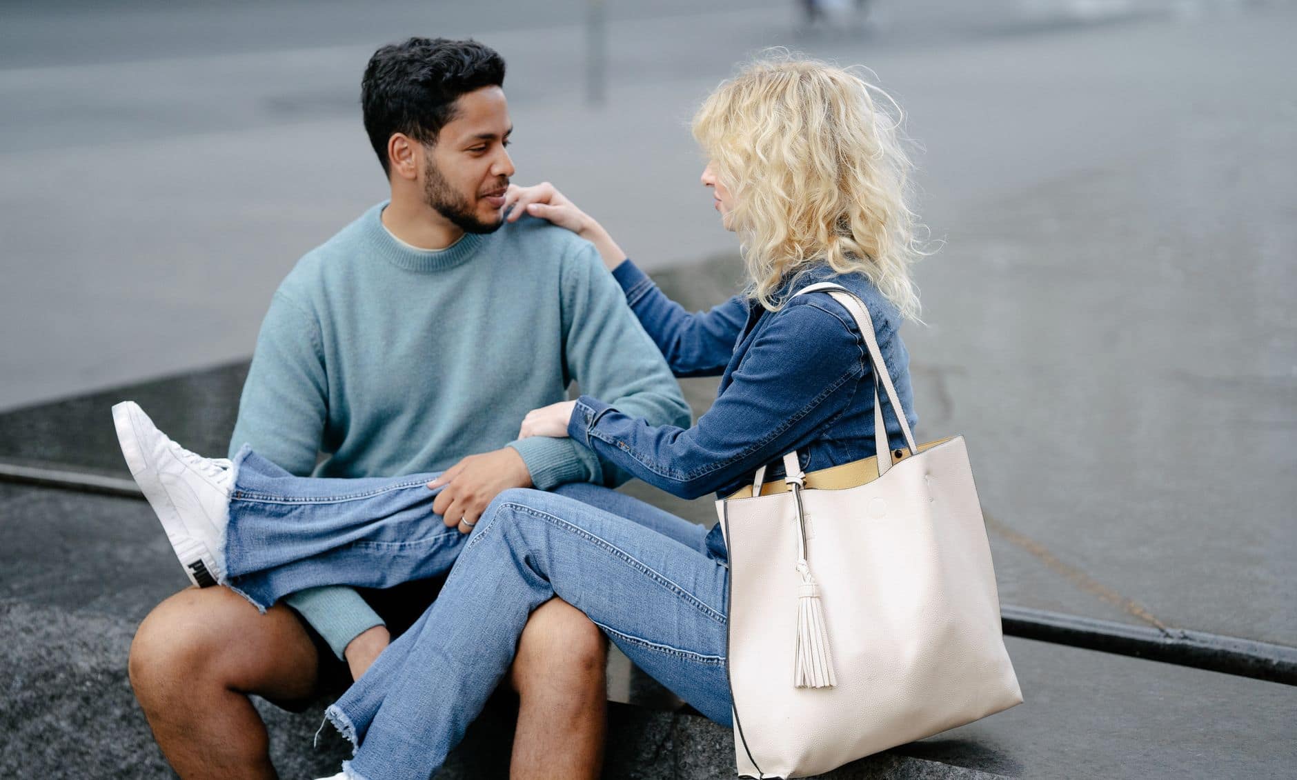 Young couple enjoying a relaxed conversation outdoors in a city setting, seated with casual attire.