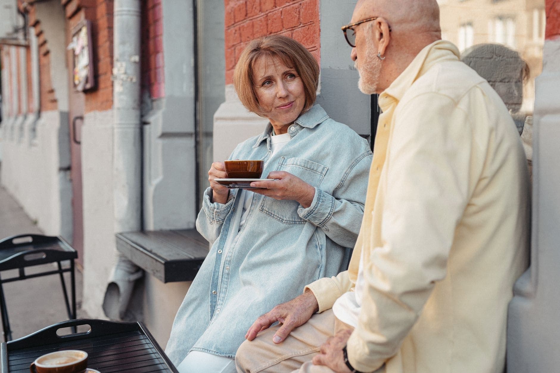Uma mulher com uma chávena conversa calmamente com um homem na esplanada de um café