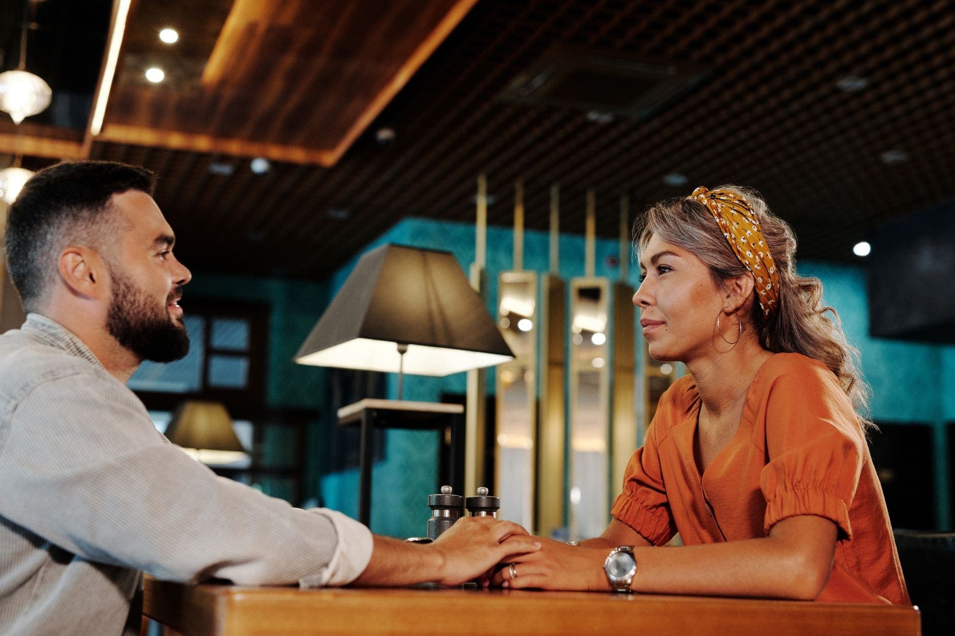 A man and a woman face each other across a restaurant table in an attentive conversation