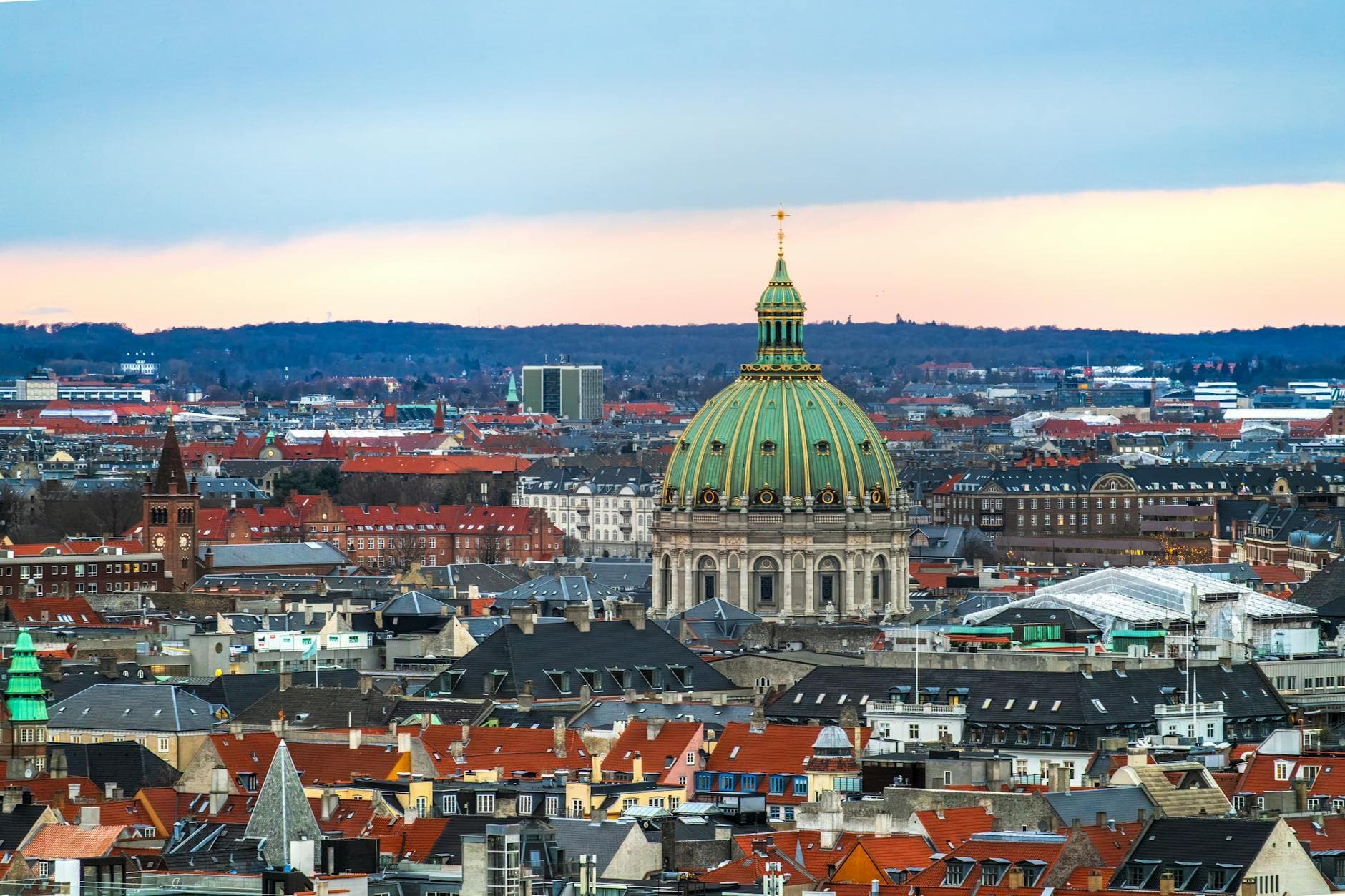 Udsigt over København i skumringen med Marmorkirkens grønne kuppel og røde tegltage.