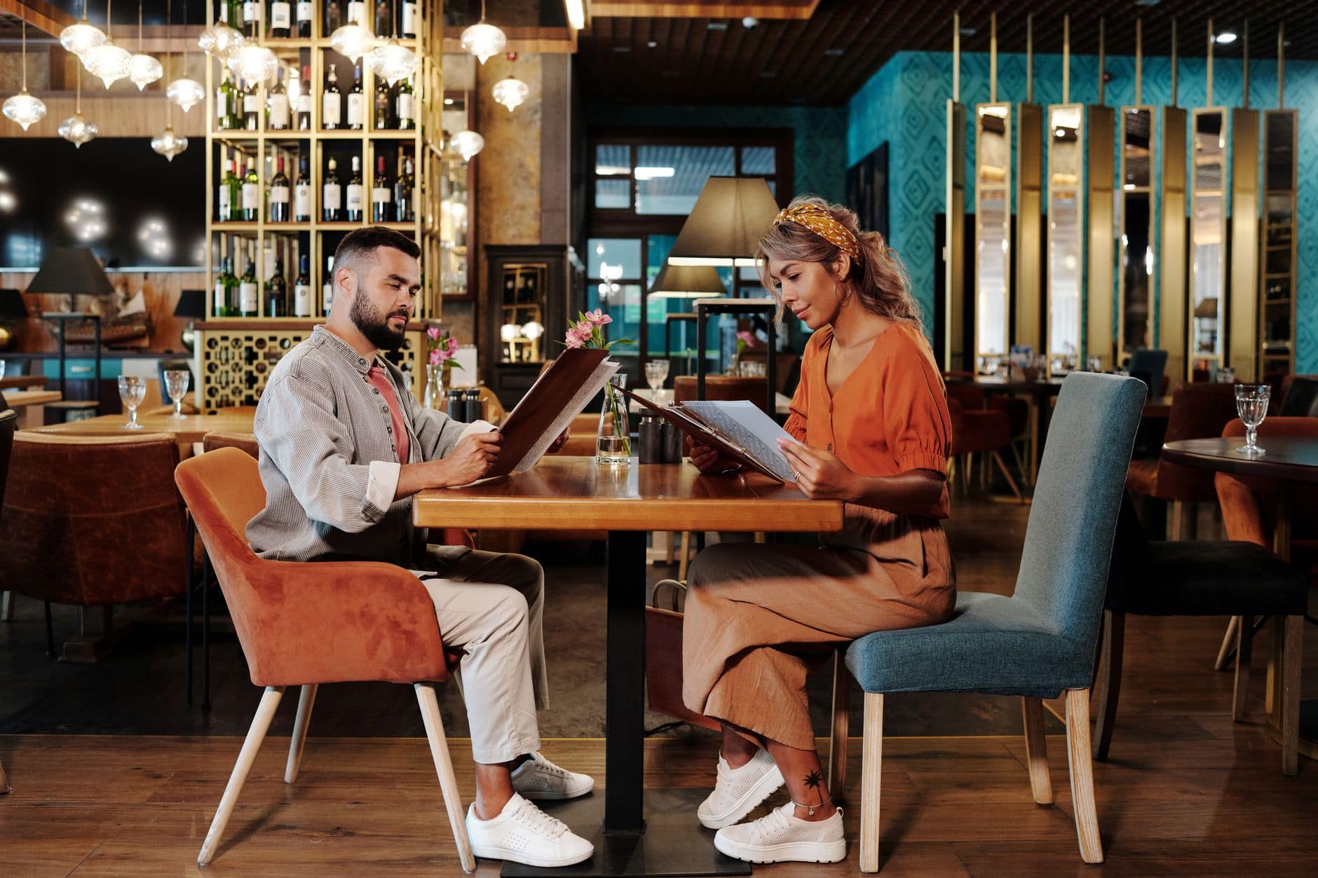 Dos personas adultas miran la carta en una mesa de restaurante.