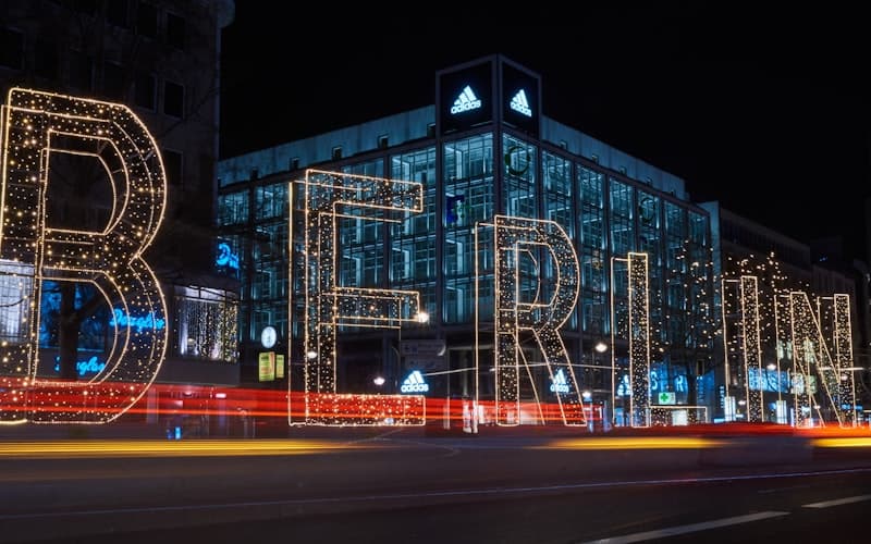 Leuchtende Buchstaben bilden nachts das Wort Berlin vor einer Glasfassade.