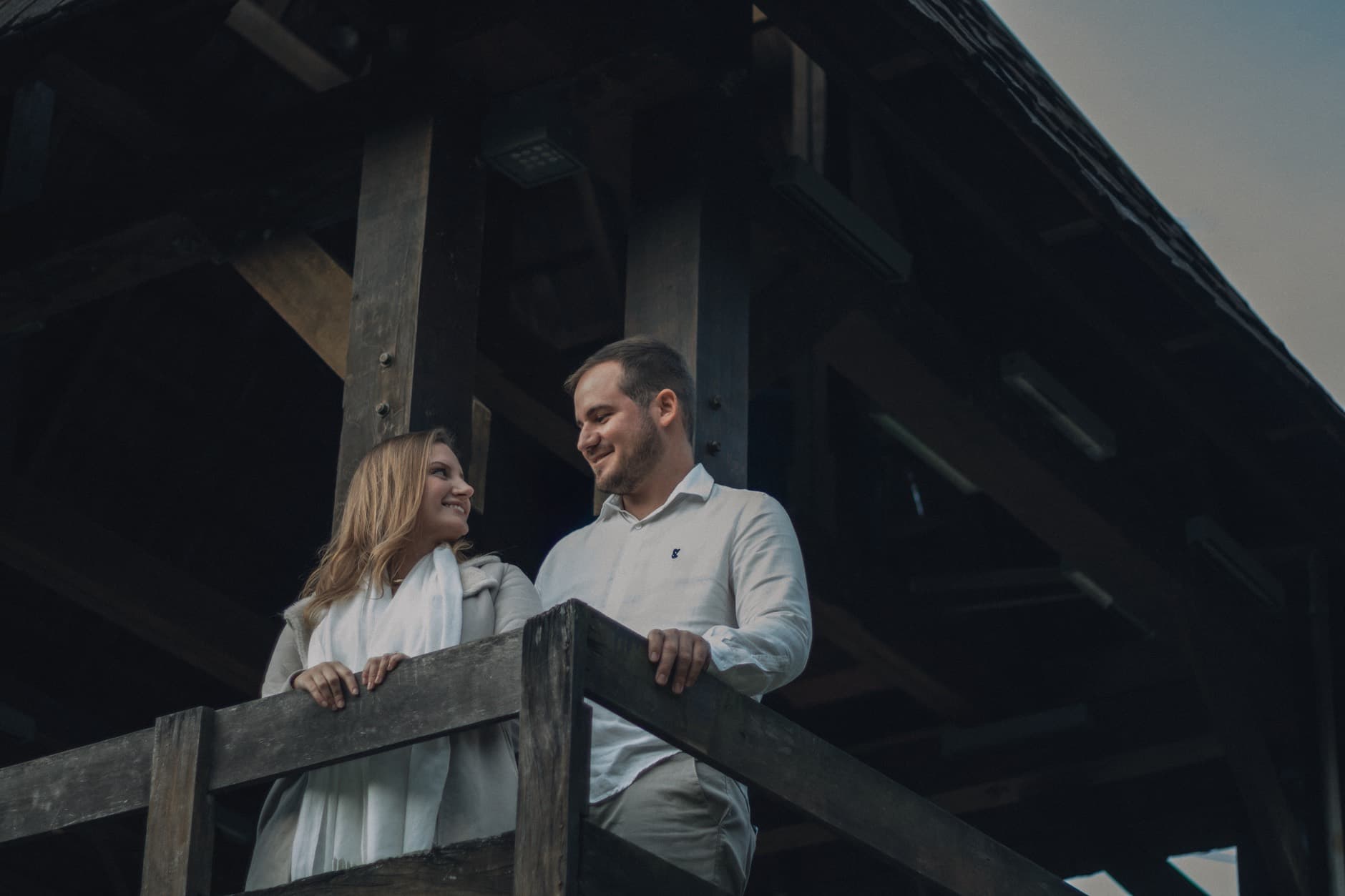 Twee mensen glimlachen naar elkaar op een houten balkon.