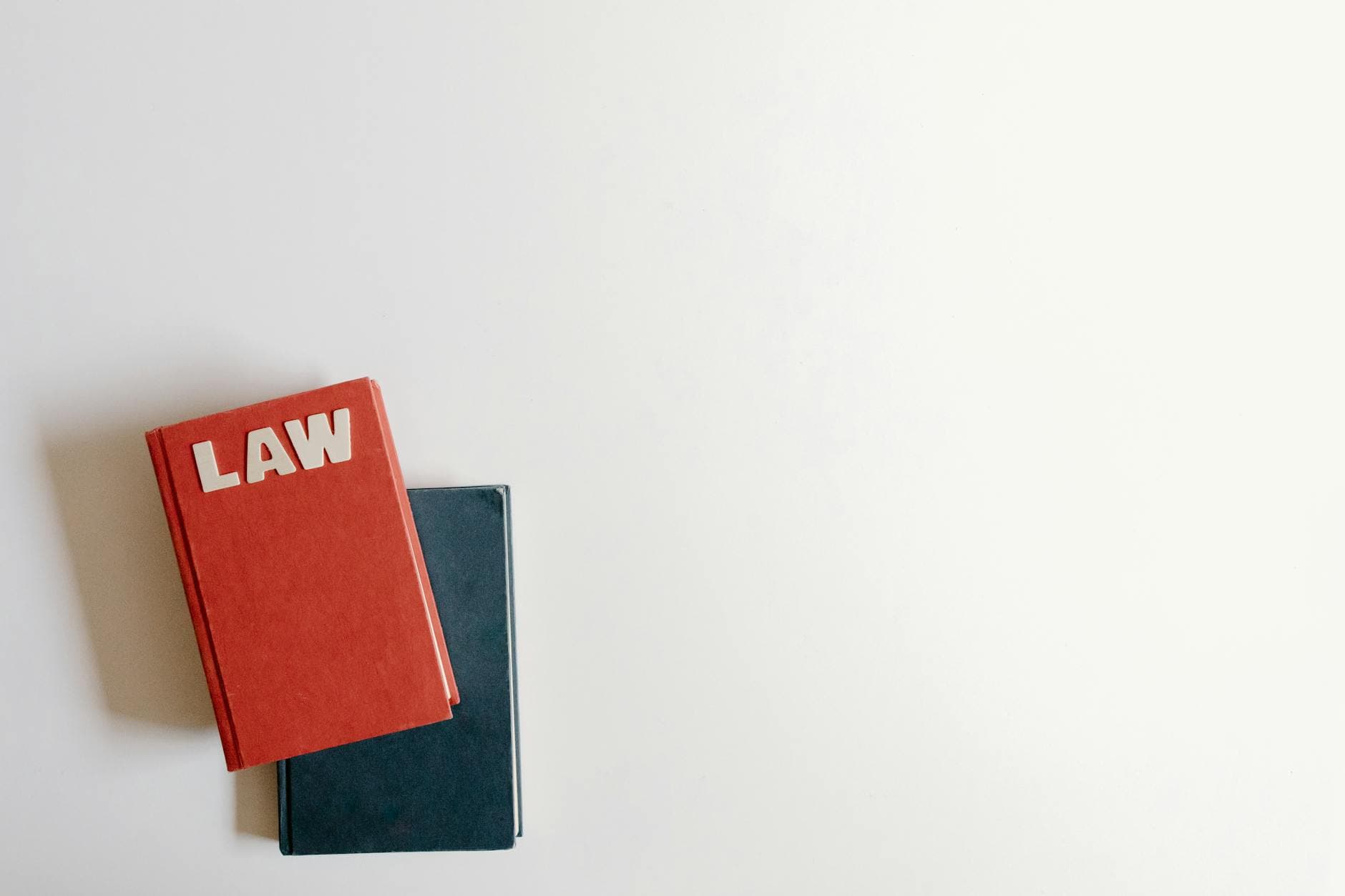 A red hardback marked LAW rests on a dark navy book against a plain white surface.