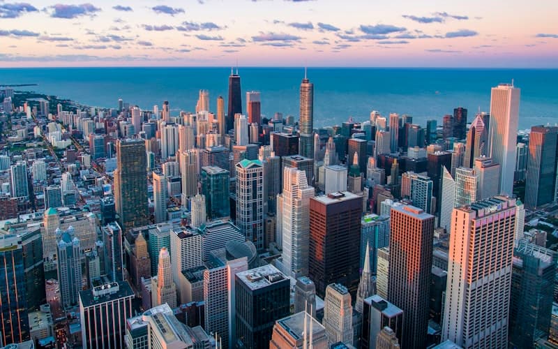 Aerial view of downtown skyscrapers along a blue lakefront at sunset.