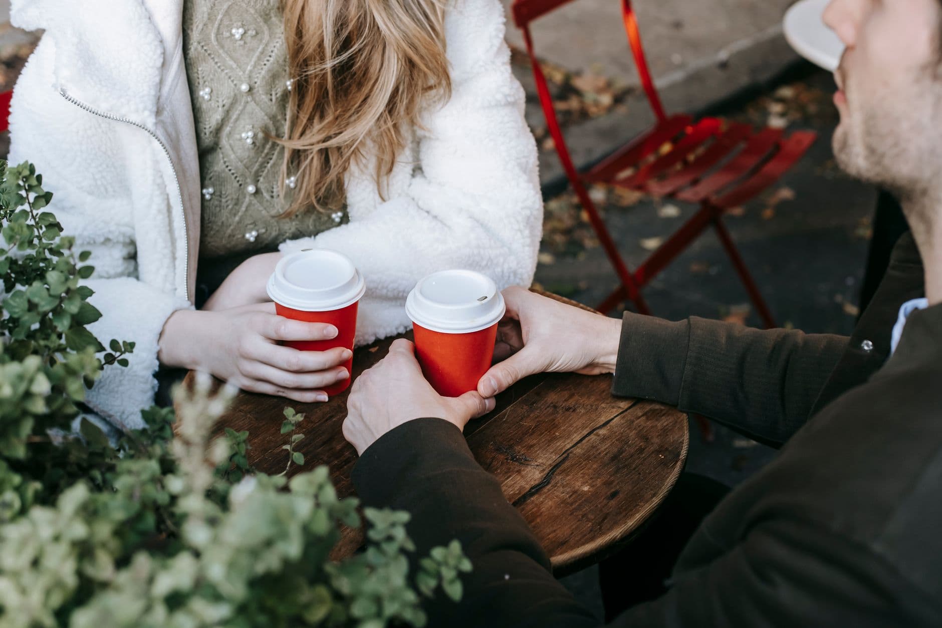 Due persone conversano con un caffè a un tavolo all'aperto.