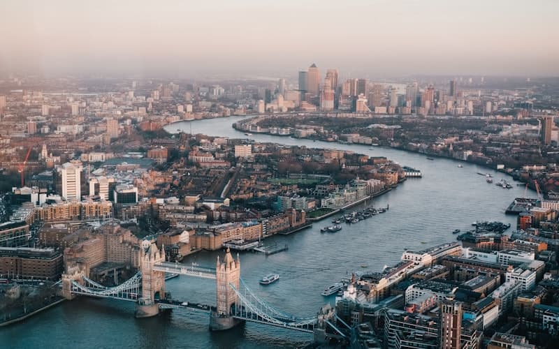 An aerial view of Tower Bridge and the river winding through the city at dusk.