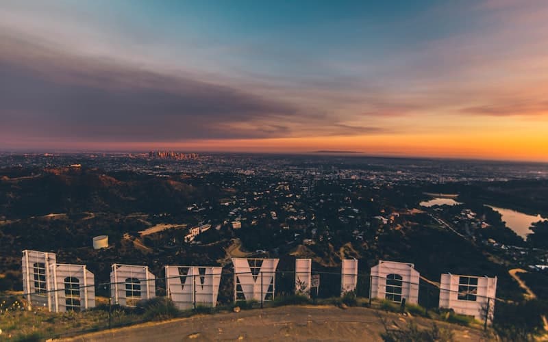 Large white letters on a hillside above a sprawling city at orange sunset.