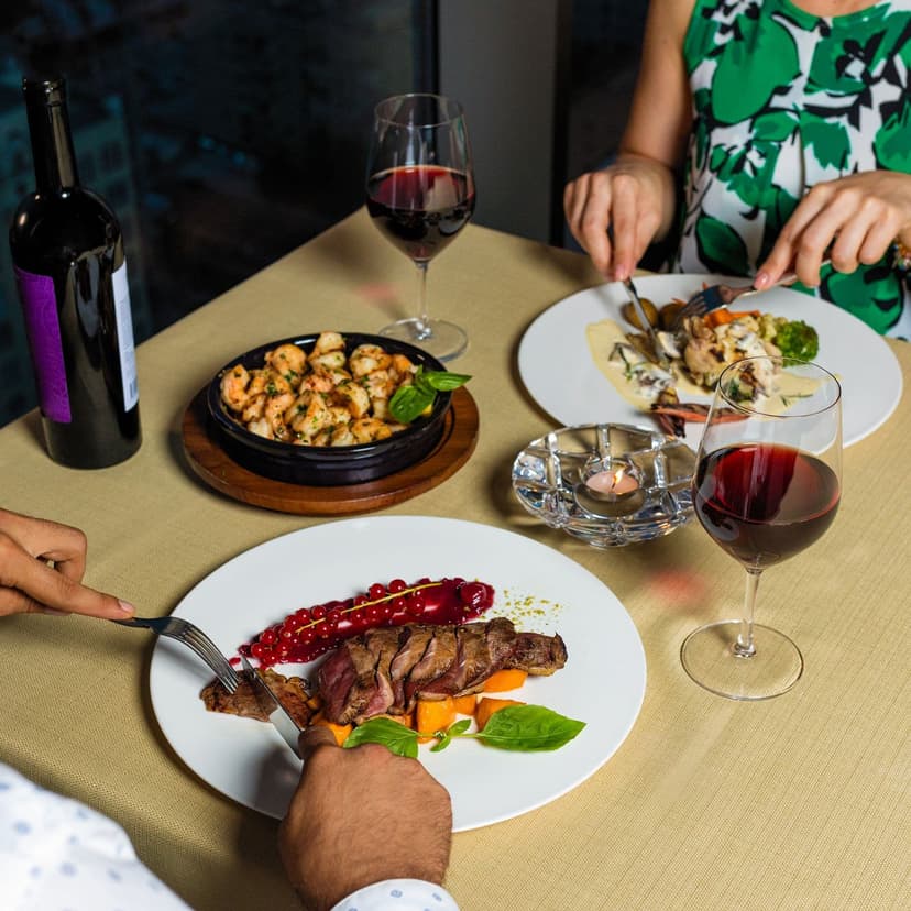 Elegant gedeckter Restauranttisch mit Rotwein und gehobenem Gericht