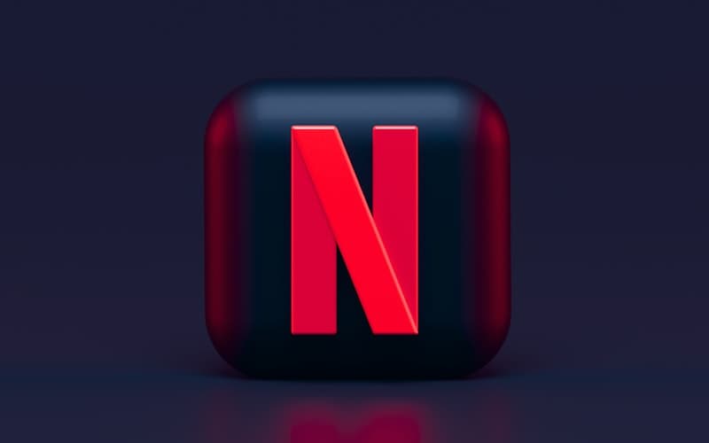 A glossy red letter N on a dark rounded tile against a deep navy background.