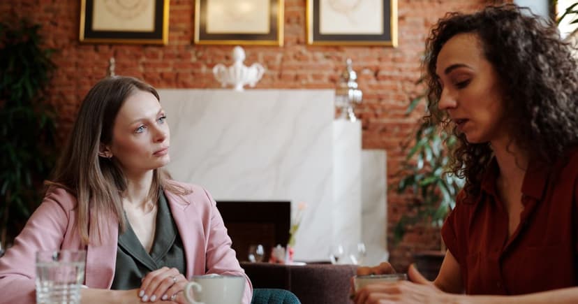 Two women having a serious conversation over coffee at a cafe table