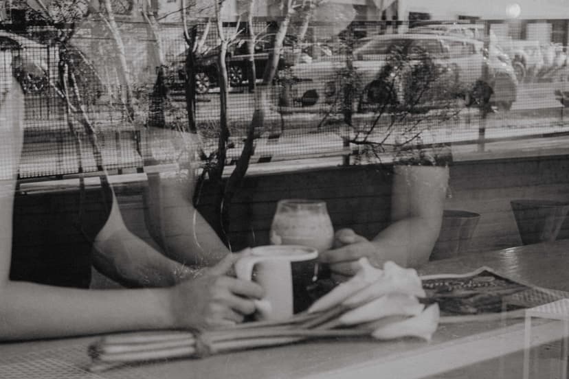 Sort-hvidt billede af et par, der holder hinanden i hånden hen over et cafébord