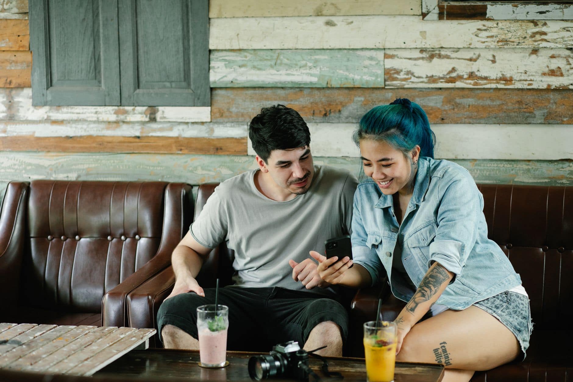 Dos personas adultas miran juntas un celular mientras están sentadas en una cafetería.