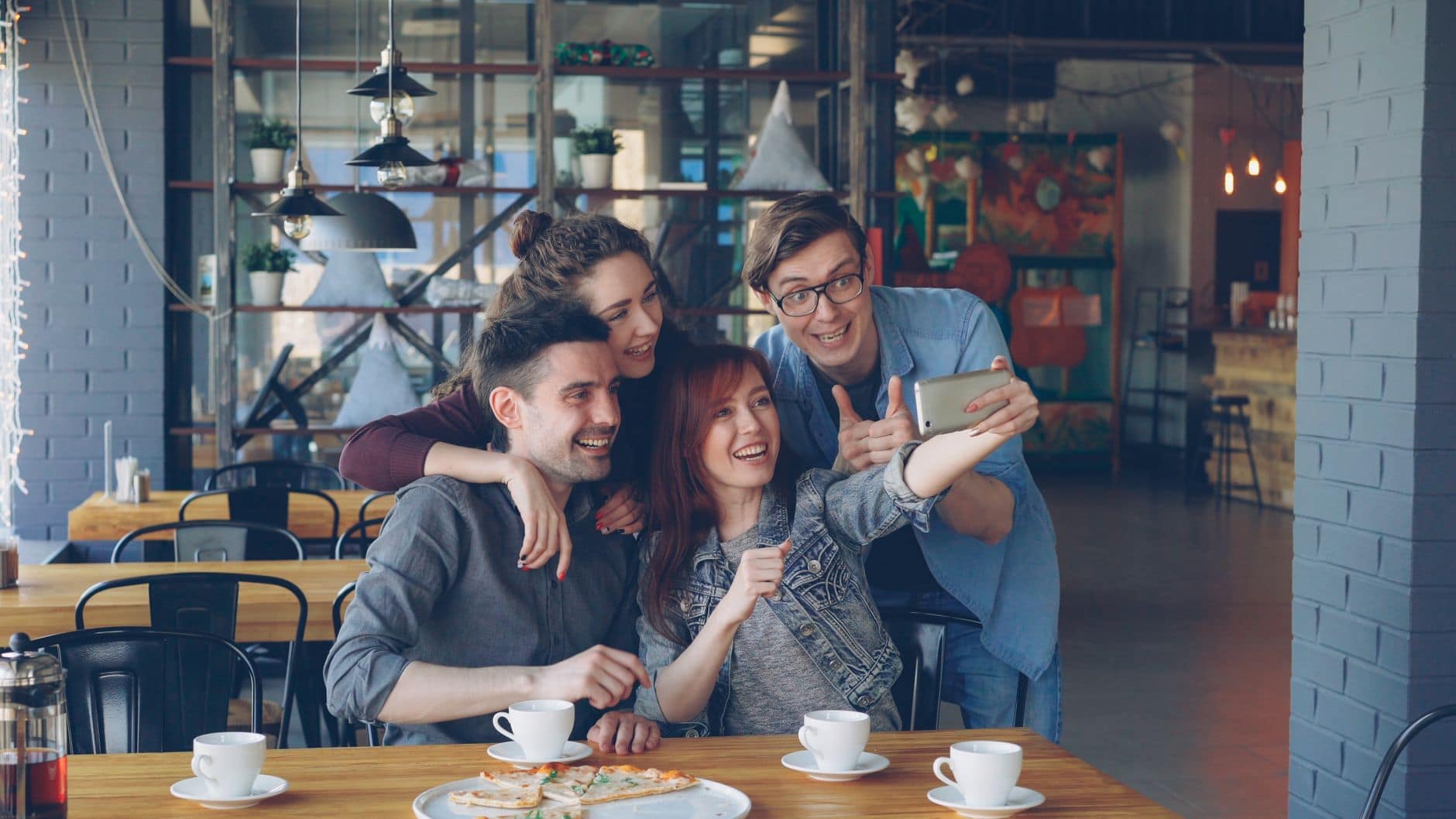 Un grupo de personas adultas sonríe para una selfie en una mesa de café.