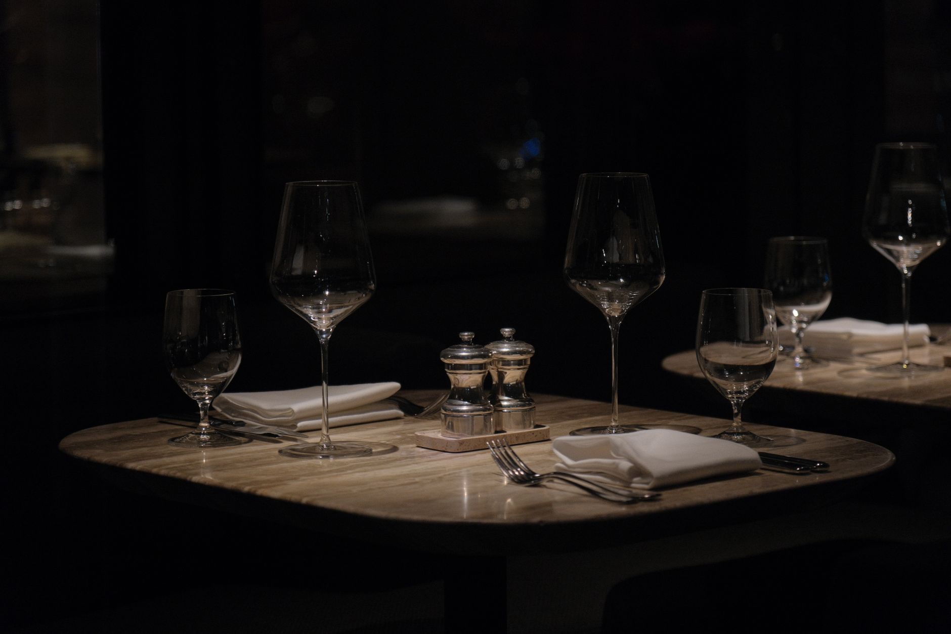The candlelit interior of an upscale restaurant in the evening, set for a quiet dinner